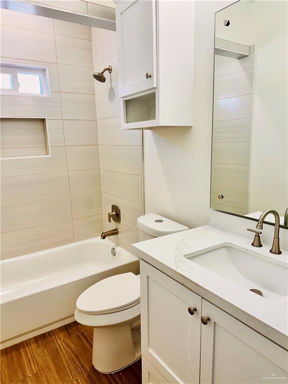 full bathroom with hardwood / wood-style floors, vanity, toilet, and tiled shower / bath