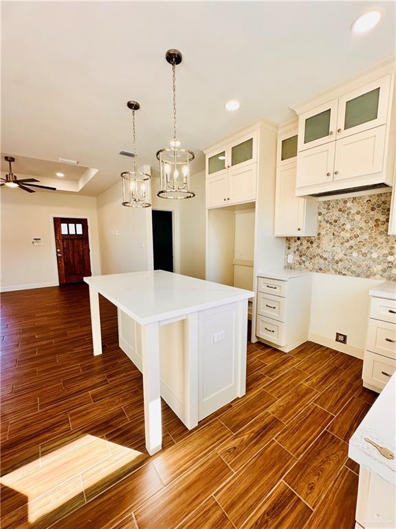 kitchen featuring tasteful backsplash, ceiling fan with notable chandelier, a kitchen island, and dark hardwood / wood-style floors