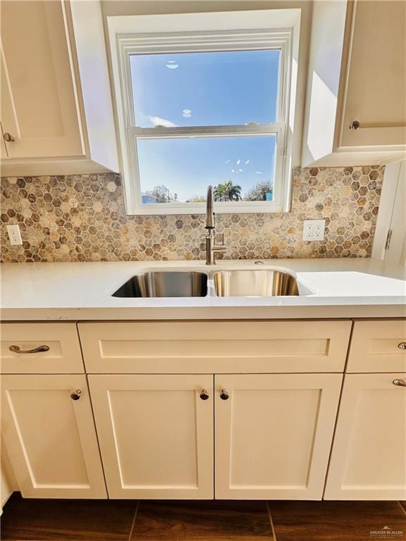 kitchen with decorative backsplash, white cabinetry, and sink