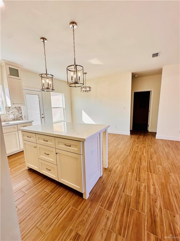 kitchen featuring light hardwood / wood-style floors, a kitchen island, white cabinetry, and hanging light fixtures