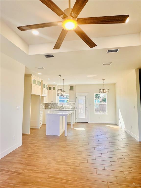 kitchen with white cabinets, light hardwood / wood-style floors, and hanging light fixtures