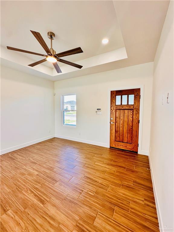 entryway featuring a tray ceiling, ceiling fan, and light hardwood / wood-style floors