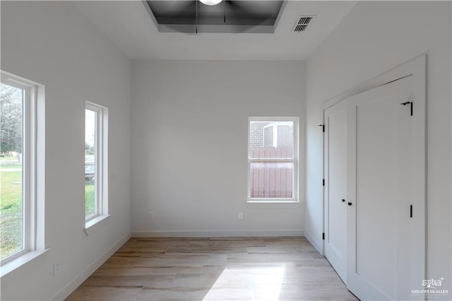 unfurnished bedroom featuring a raised ceiling and light hardwood / wood-style flooring