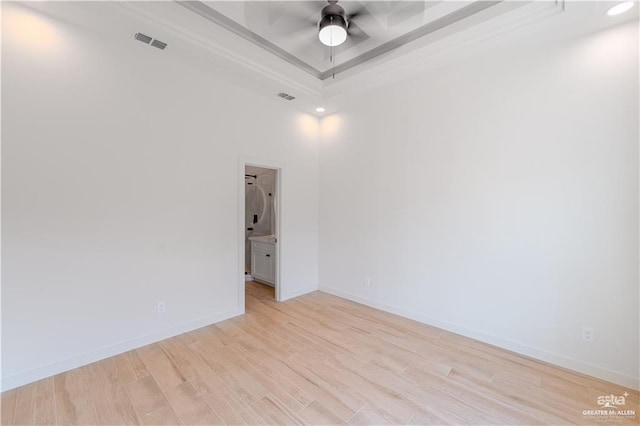 spare room with a raised ceiling, light hardwood / wood-style flooring, ceiling fan, and ornamental molding