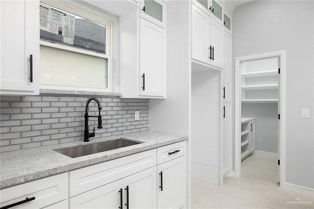 905 Magnolia St, Mission, TX 78574 - kitchen with a sink, backsplash, light stone countertops, white cabinets, and glass insert cabinets