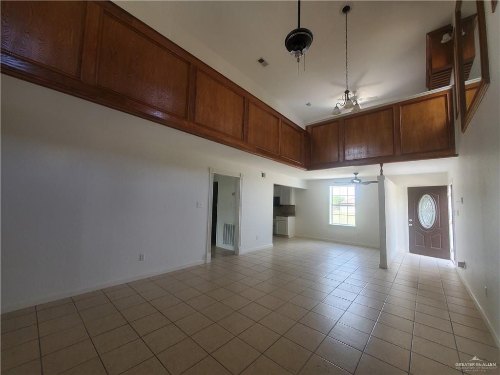 spare room featuring ceiling fan, a towering ceiling, and light tile patterned floors