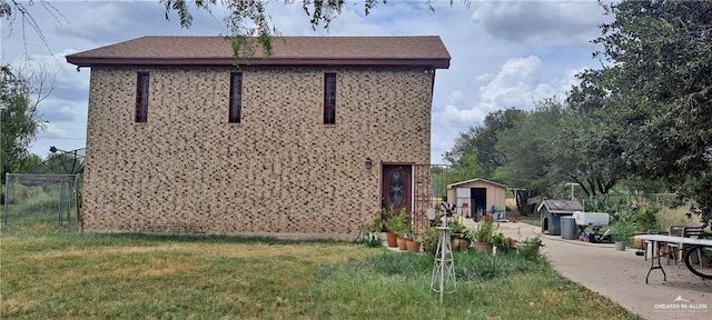 view of side of property featuring a yard and a storage unit