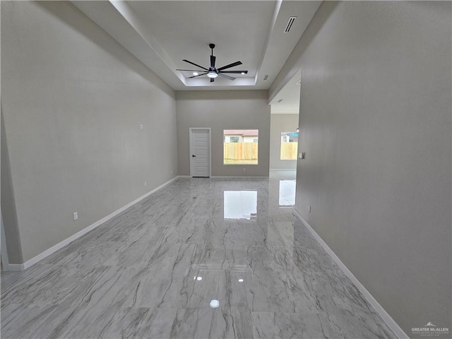 unfurnished living room with a tray ceiling and ceiling fan