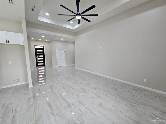 spare room featuring ceiling fan and a raised ceiling