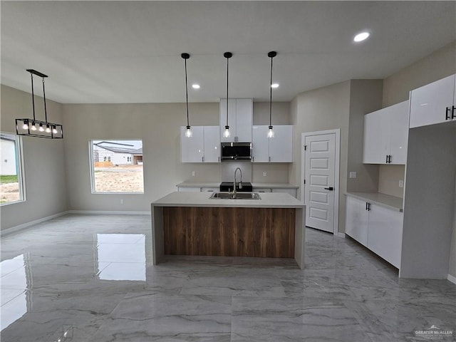 kitchen with sink, white cabinetry, plenty of natural light, decorative light fixtures, and an island with sink