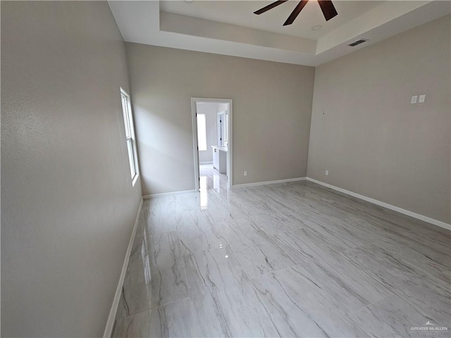 unfurnished room featuring ceiling fan and a raised ceiling