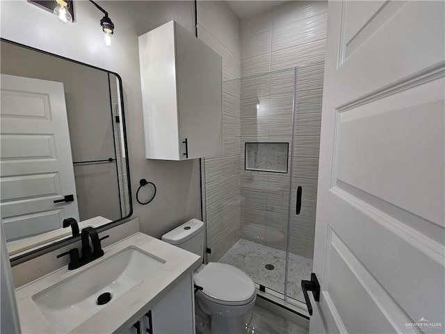 bathroom with toilet, vanity, and a shower with shower door