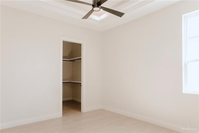 unfurnished bedroom featuring light wood-style flooring, a spacious closet, baseboards, and a closet