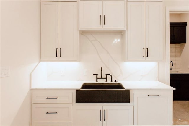 kitchen featuring white cabinets, light countertops, and a sink