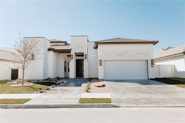 view of front facade featuring concrete driveway, an attached garage, fence, and stucco siding