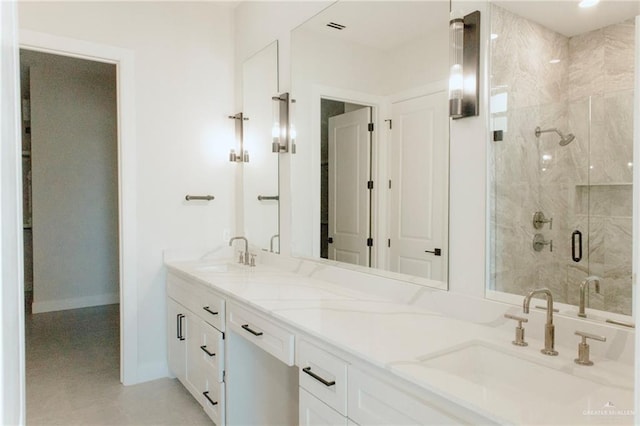 full bath featuring double vanity, a stall shower, baseboards, and a sink