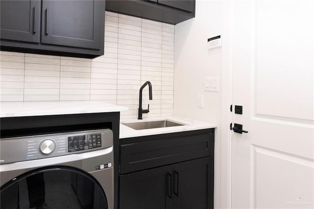 washroom with washer / clothes dryer, a sink, and cabinet space