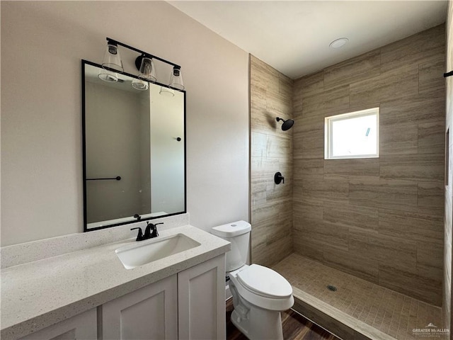 bathroom with toilet, vanity, and tiled shower