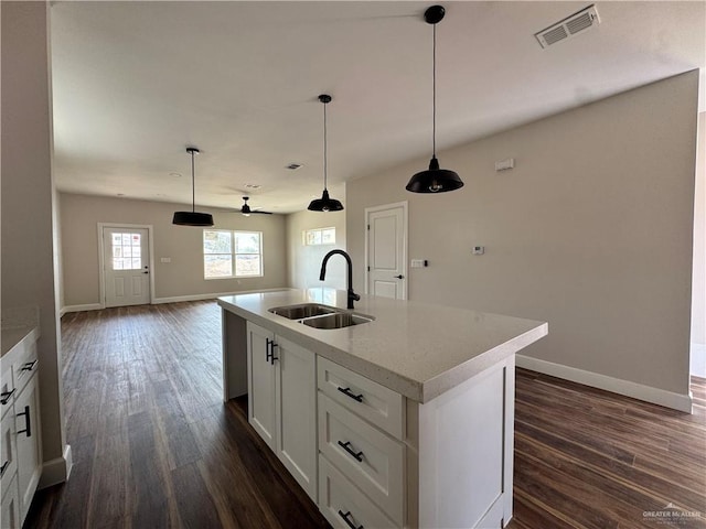kitchen featuring visible vents, a sink, baseboards, a kitchen island with sink, and dark wood-style flooring