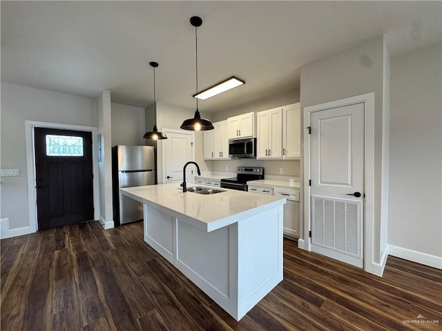 1604 Monterrey Cir, Brownsville, TX 78526 - kitchen with stainless steel appliances, dark wood-style floors, a kitchen island with sink, white cabinets, and hanging light fixtures