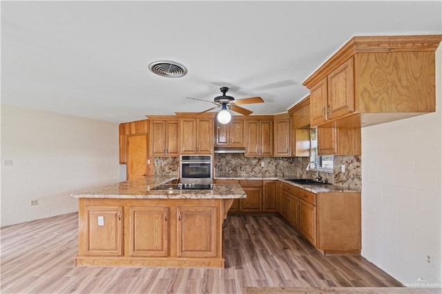 kitchen with hardwood / wood-style flooring, sink, stainless steel oven, and kitchen peninsula