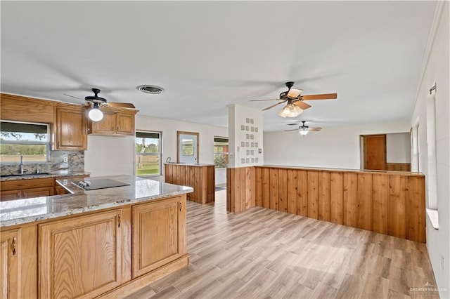 kitchen with light hardwood / wood-style flooring, light stone countertops, black electric cooktop, backsplash, and sink