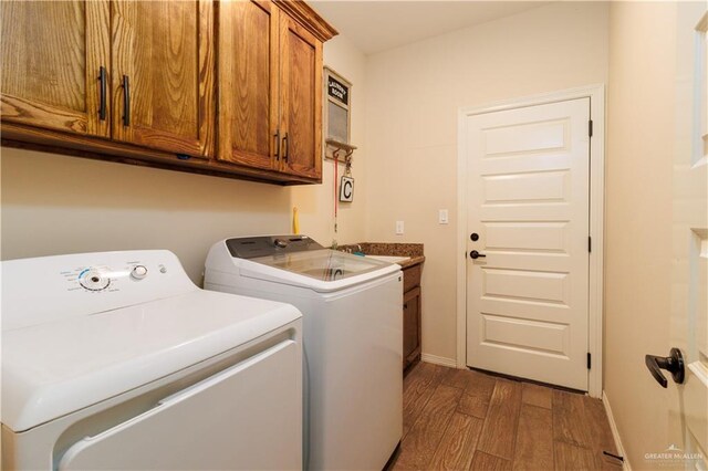 clothes washing area featuring a sink, dark wood-type flooring, baseboards, separate washer and dryer, and cabinet space