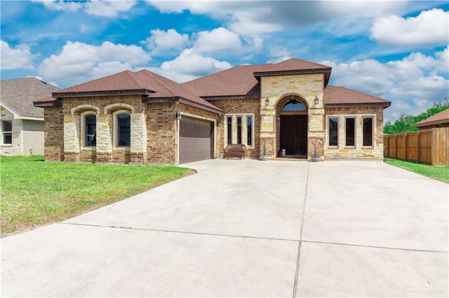 mediterranean / spanish-style house with concrete driveway, a front lawn, fence, a garage, and brick siding
