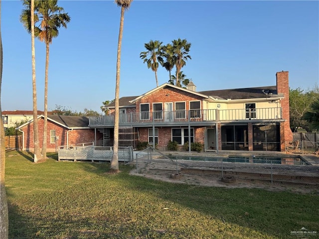 1060 Timothy St, San Benito, TX 78586 - back of property with brick siding, a lawn, a balcony, a chimney, and a wooden deck