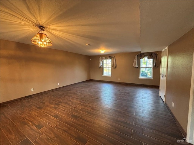 1060 Timothy St, San Benito, TX 78586 - spare room featuring dark wood-style flooring, a textured ceiling, and a chandelier