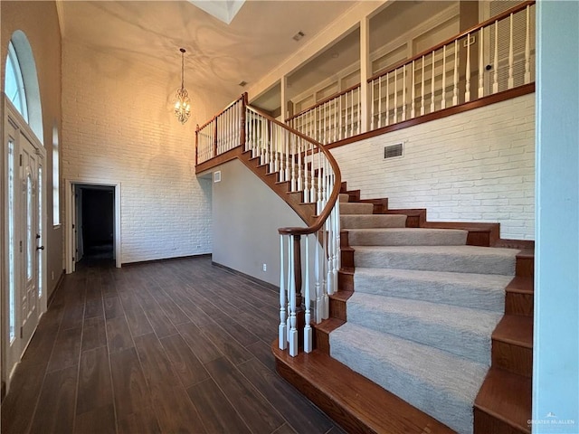 1060 Timothy St, San Benito, TX 78586 - staircase with brick wall, a high ceiling, a chandelier, and wood finished floors