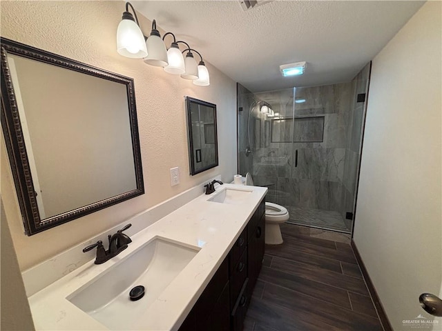 1060 Timothy St, San Benito, TX 78586 - full bathroom featuring a stall shower, a textured ceiling, double vanity, and wood finished floors