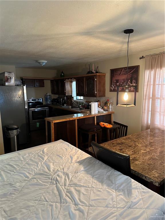 bedroom with stainless steel fridge, a textured ceiling, and sink