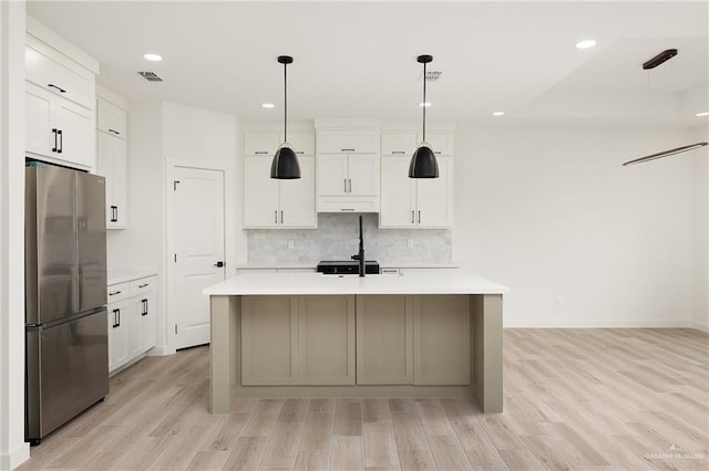 3508 E Kidd Ave, Edinburg, TX 78542 - kitchen with freestanding refrigerator, light countertops, light wood-type flooring, tasteful backsplash, and a center island with sink