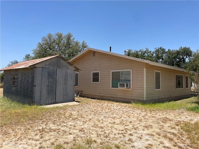 rear view of property featuring an outdoor structure and cooling unit