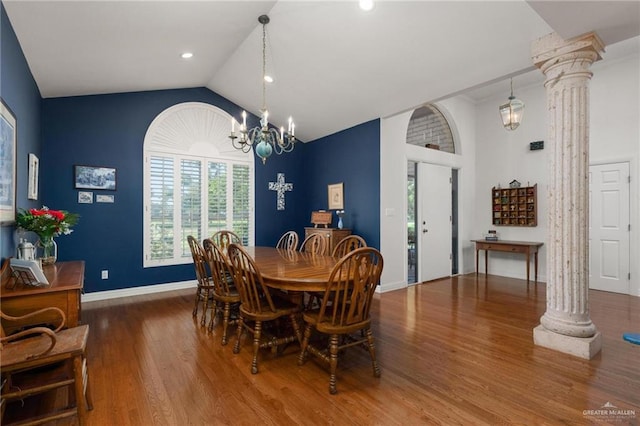 dining space featuring a chandelier, vaulted ceiling, wood-type flooring, and decorative columns