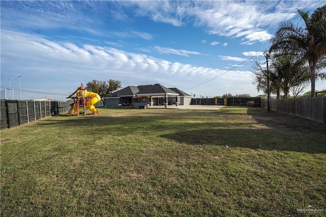 view of yard featuring playground community and a fenced backyard