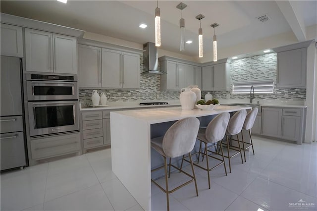 kitchen with visible vents, refrigerator, wall chimney exhaust hood, and gray cabinetry