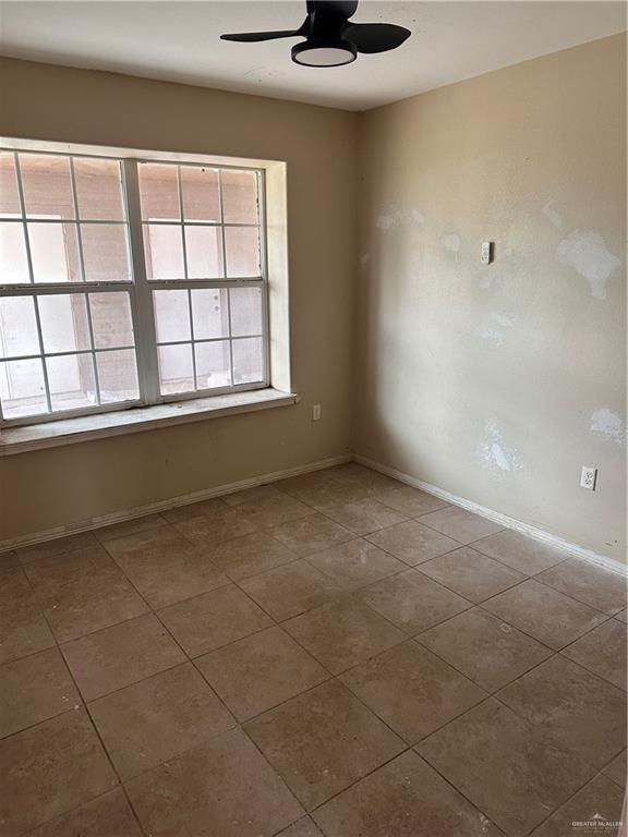 spare room featuring tile patterned floors and ceiling fan