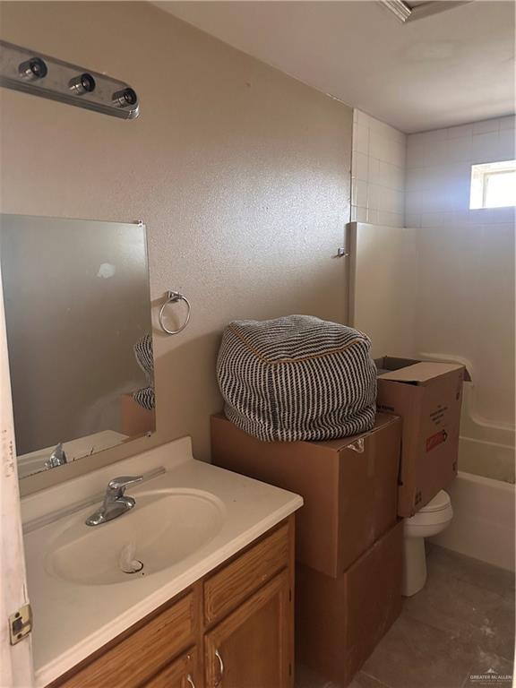 full bathroom featuring vanity, tiled shower / bath combo, and toilet