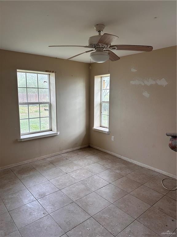 empty room featuring ceiling fan, a healthy amount of sunlight, and light tile patterned flooring