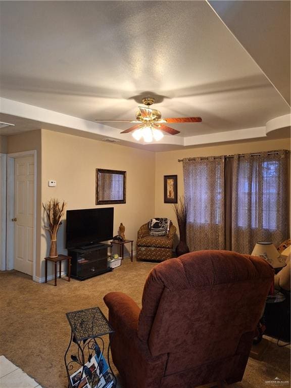 carpeted living room featuring ceiling fan and a raised ceiling