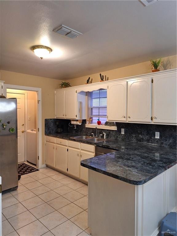 kitchen with white cabinets, sink, kitchen peninsula, and stainless steel fridge