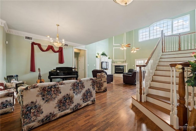 living room with a towering ceiling, ceiling fan with notable chandelier, and hardwood / wood-style flooring