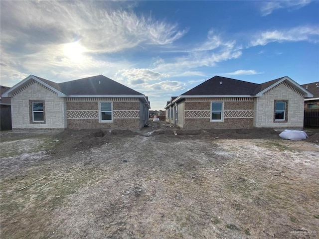 view of home's exterior featuring stone siding, fence, and brick siding