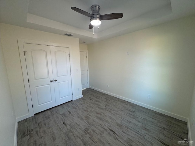 unfurnished bedroom with a closet, a raised ceiling, and ceiling fan