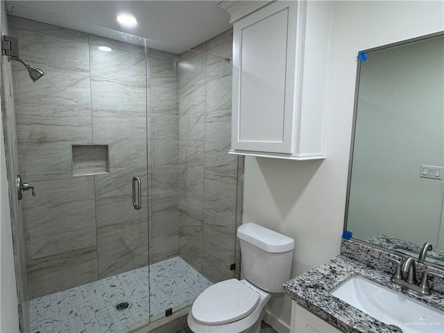 bathroom featuring vanity, a shower with shower door, and toilet