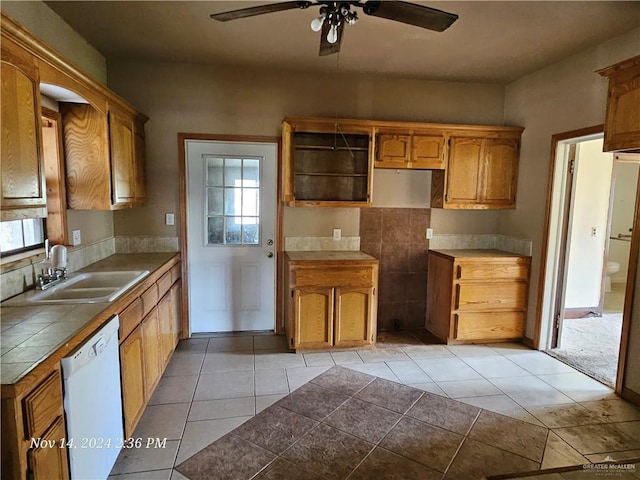 kitchen featuring ceiling fan, dishwasher, sink, tile countertops, and light tile patterned floors