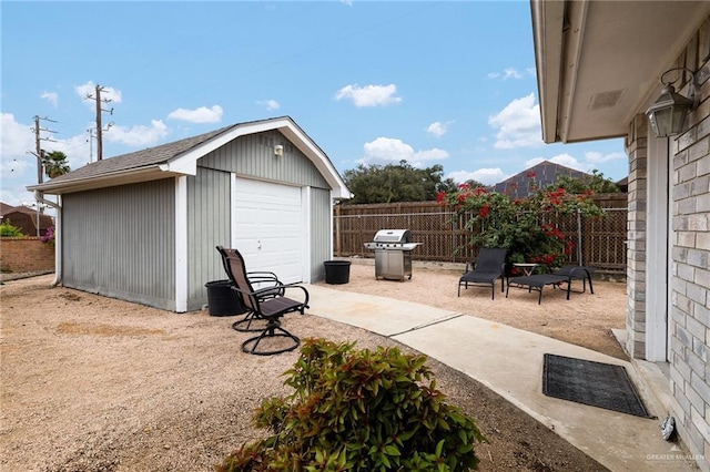 view of patio / terrace with a garage, an outdoor structure, and a grill