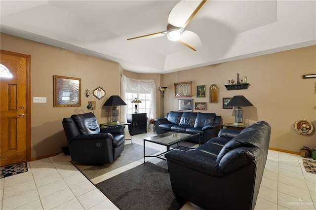 living room featuring a raised ceiling, ceiling fan, and light tile patterned flooring